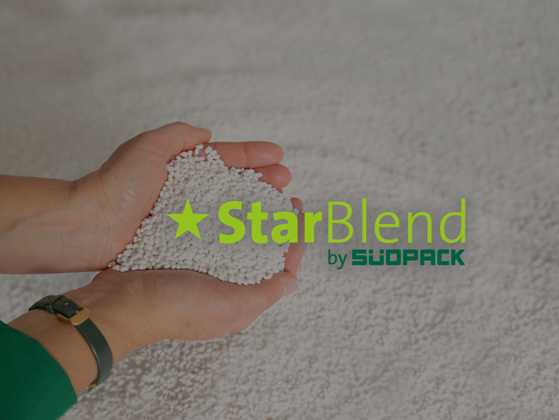 A hand holding the innovative StarBlend® Compound from SÜDPACK, made from conventional and biobased raw materials, featuring the StarBlend logo.